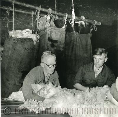09-00530.jpg; FLM-09-00530; Foto in zwart-wit van drie mannen die schapenvachten in zakken doen door S. Andringa, 1960; foto
