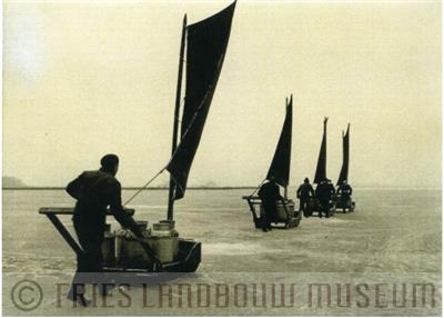 09-01594.jpg; FLM-09-01594; Foto in zwart-wit van het vervoer van melkbussen over ijs door S. Andringa, 1955; foto